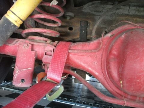 1972 Ford Ranchero - Close-up view of the rear axle and suspension components, secured with a red tie-down strap.