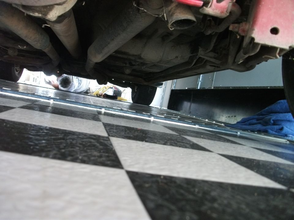 Undercarriage view of a vehicle with exhaust pipes and a person lying underneath