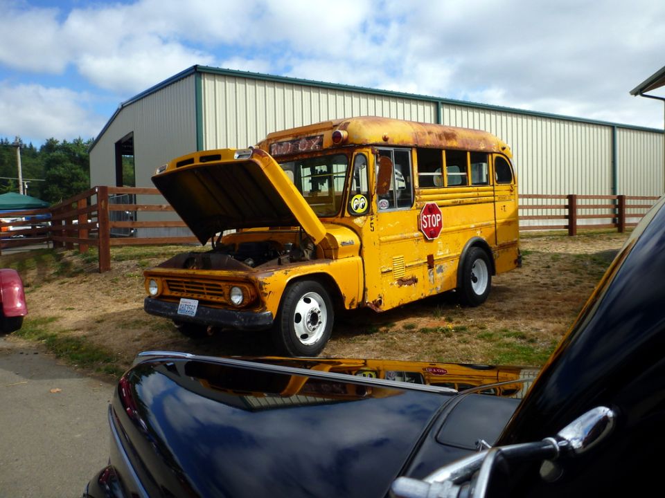 Yellow school bus with hood open, parked outside a building