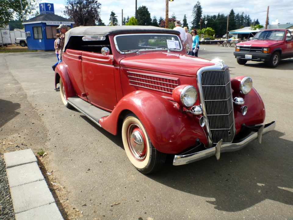 Red 1936 convertible with whitewall tires and black top, seen from a 3/4 front angle
