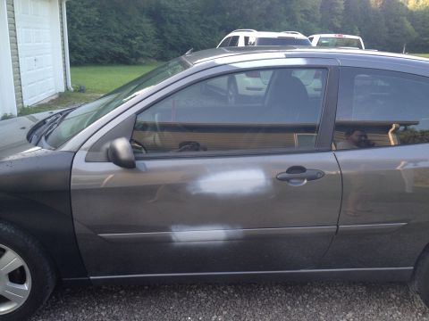 2007 Ford Mustang - The side of a gray 2007 Ford Focus shows primer spots on the door, indicating recent bodywork.