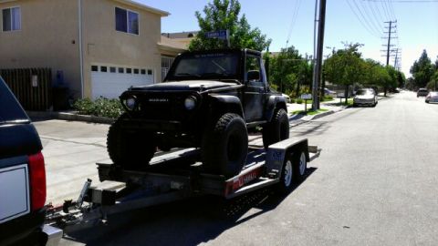 1987 Suzuki Samurai - A black 1987 Suzuki Samurai is loaded onto a U-Haul trailer, ready for transport.