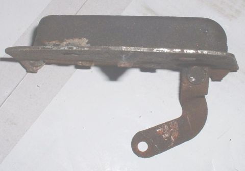 1986 Ford Bronco - A corroded metal bracket with a single mounting hole is shown against a white background.