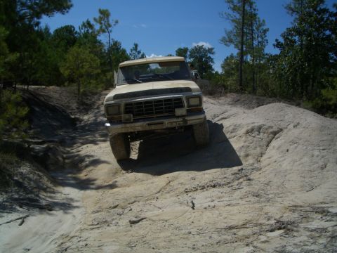 1979 Ford Bronco - This truck is navigating a challenging off-road terrain with a sandy incline.