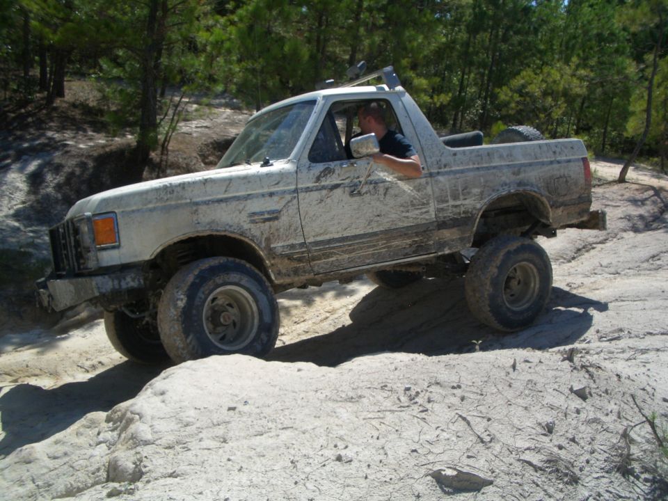 1979 Ford Bronco driving off-road, covered in mud