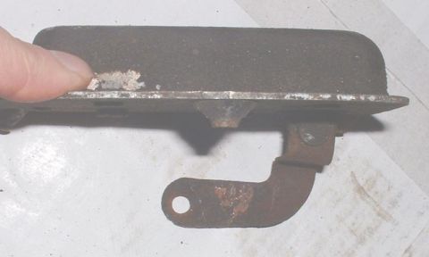 1986 Ford Bronco - Close-up of a rusted metal bracket, with a finger visible.