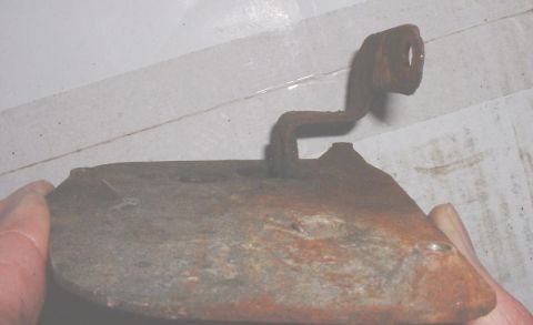 1986 Ford Bronco - A close-up view of a heavily rusted metal bracket with an L-shaped arm.