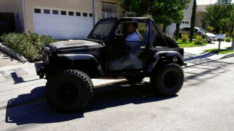 1987 Suzuki Samurai - Modified 1987 Suzuki Samurai with custom paint and large off-road tires is seen driving on a street.