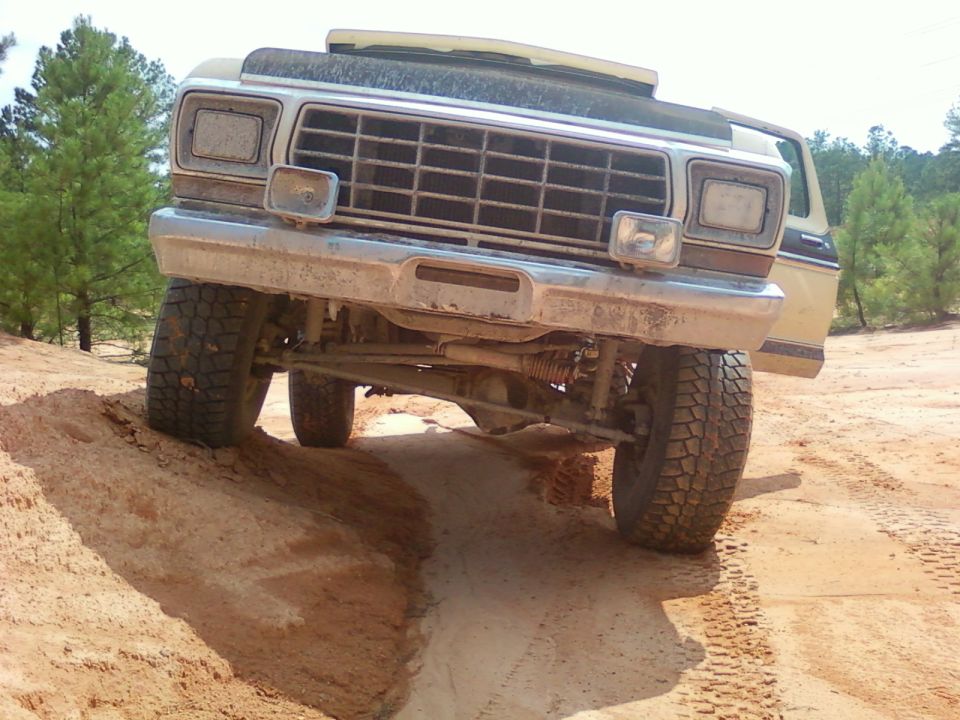 Tan 1978 Ford Bronco driving off-road, front view, dusty