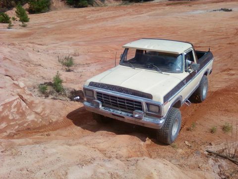 1979 Ford Bronco - 1979 Ford F-150 pickup truck navigating a dirt trail with a two-tone paint scheme and sun visor.
