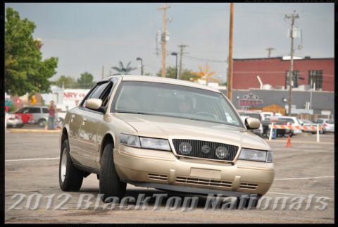 2000 Mercury Grand Marquis - A gold 2000 Mercury Grand Marquis is shown from the front three-quarter angle in an outdoor setting.