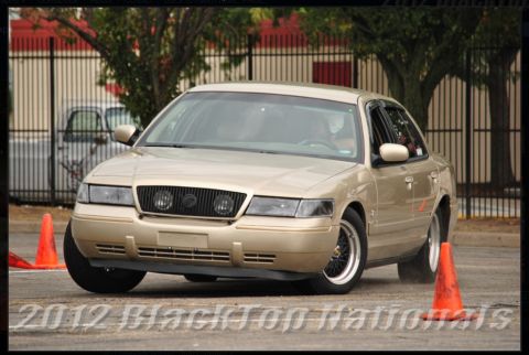 2000 Mercury Grand Marquis - A gold 2000 Mercury Grand Marquis is shown during a timed event, maneuvering around orange cones.