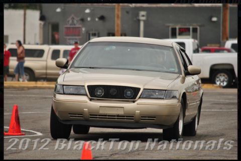2000 Mercury Grand Marquis - A gold Mercury Grand Marquis navigates a course marked by orange cones.