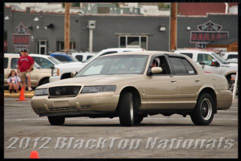 2000 Mercury Grand Marquis - A tan 2000 Mercury Grand Marquis sedan is seen in a 3q-front view, participating in an event with other vehicles in the background.