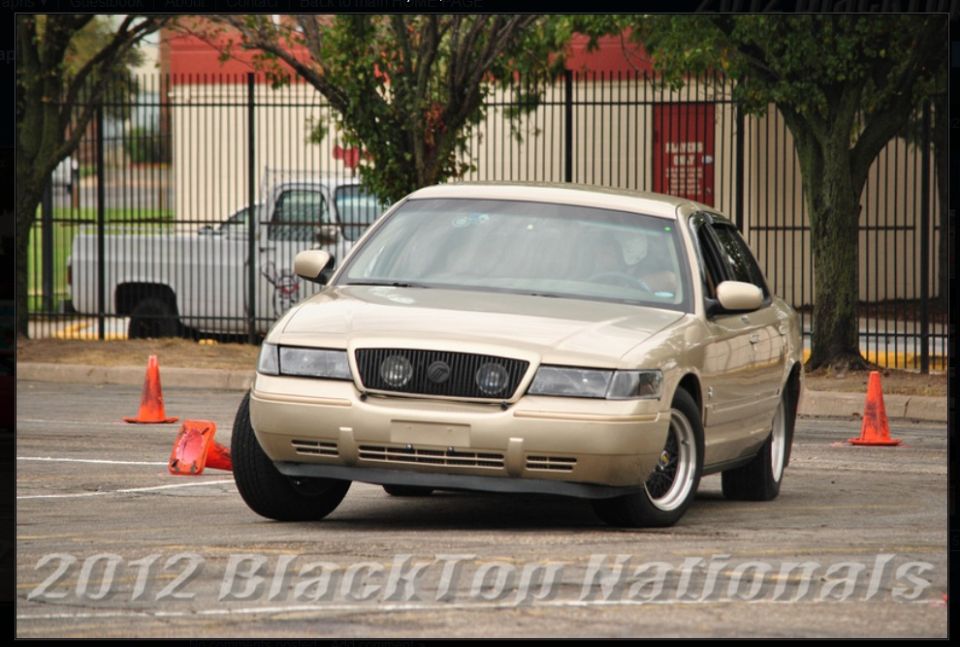 Gold 2000 Mercury Grand Marquis on a race track with orange cones