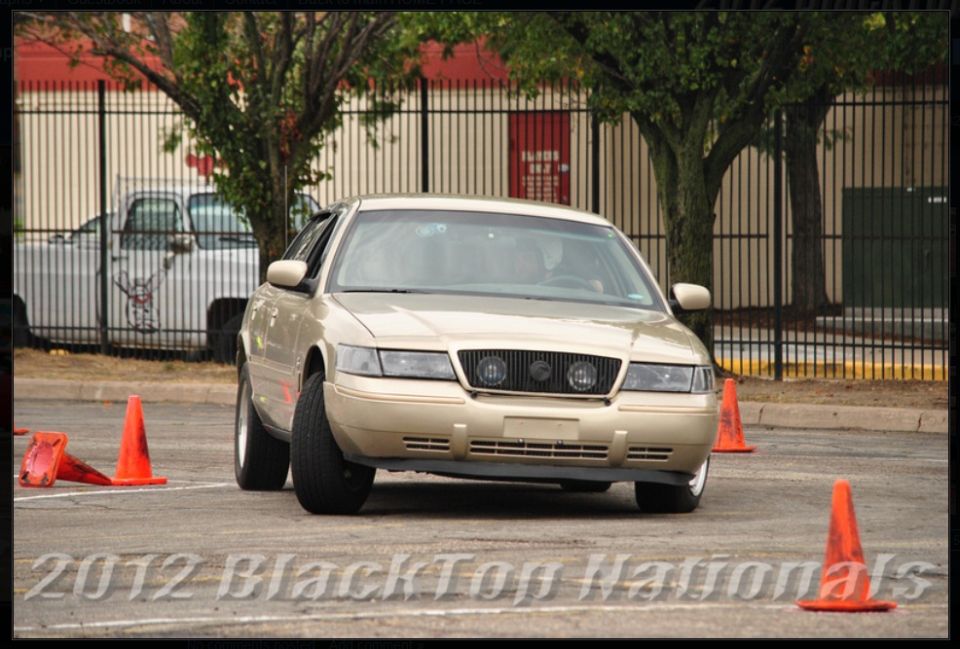 Gold 2000 Mercury Grand Marquis driving through cones