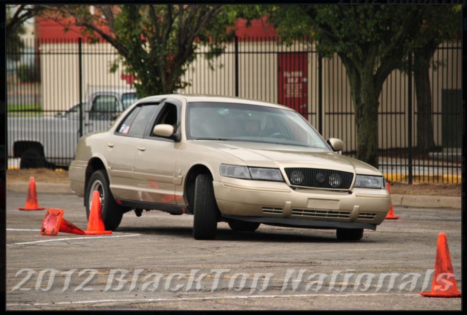Gold 2000 Mercury Grand Marquis sedan on a race track with orange cones