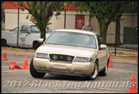 2000 Mercury Grand Marquis - Tan 2000 Mercury Grand Marquis navigates an autocross course marked by orange cones.