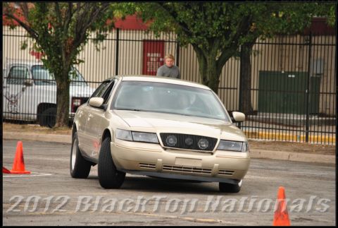 2000 Mercury Grand Marquis - A gold Ford Crown Victoria is shown from the front, maneuvering around traffic cones on a paved surface.