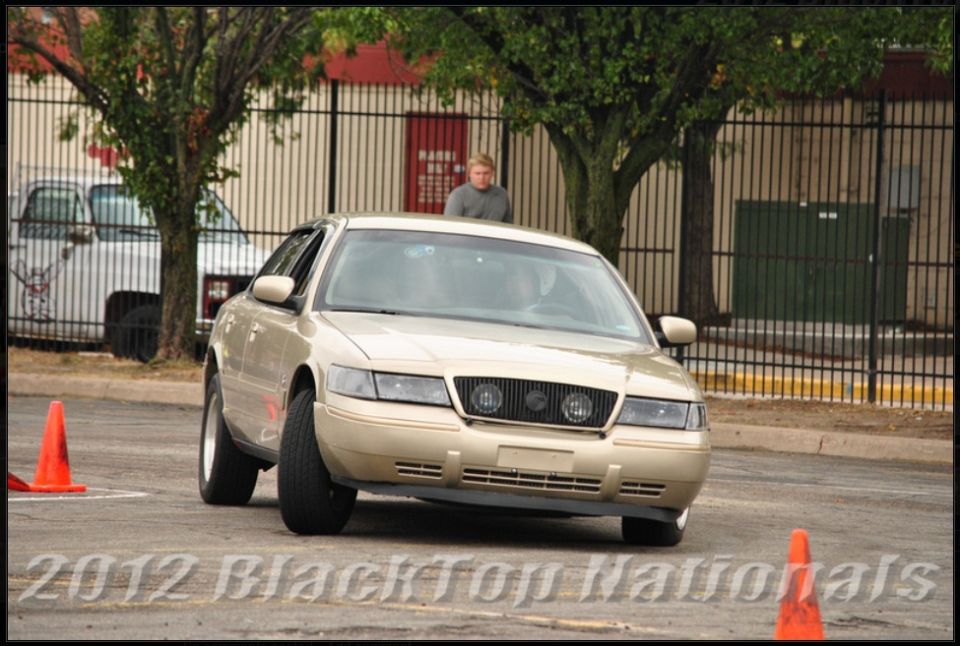 Gold Ford Crown Victoria navigating a course with orange cones