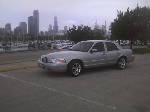 2003 Ford Crown Victoria - A silver 2003 Ford Crown Victoria is parked near a marina, with the Chicago skyline in the distance.