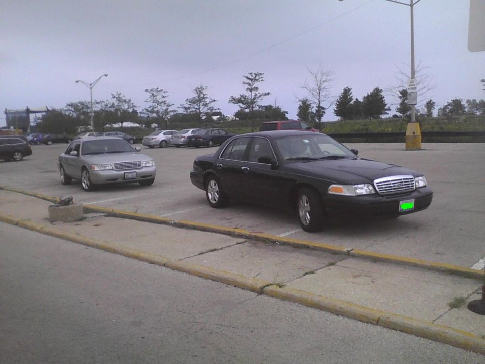 Black 2003 Ford Crown Victoria parked next to a silver one in a parking lot