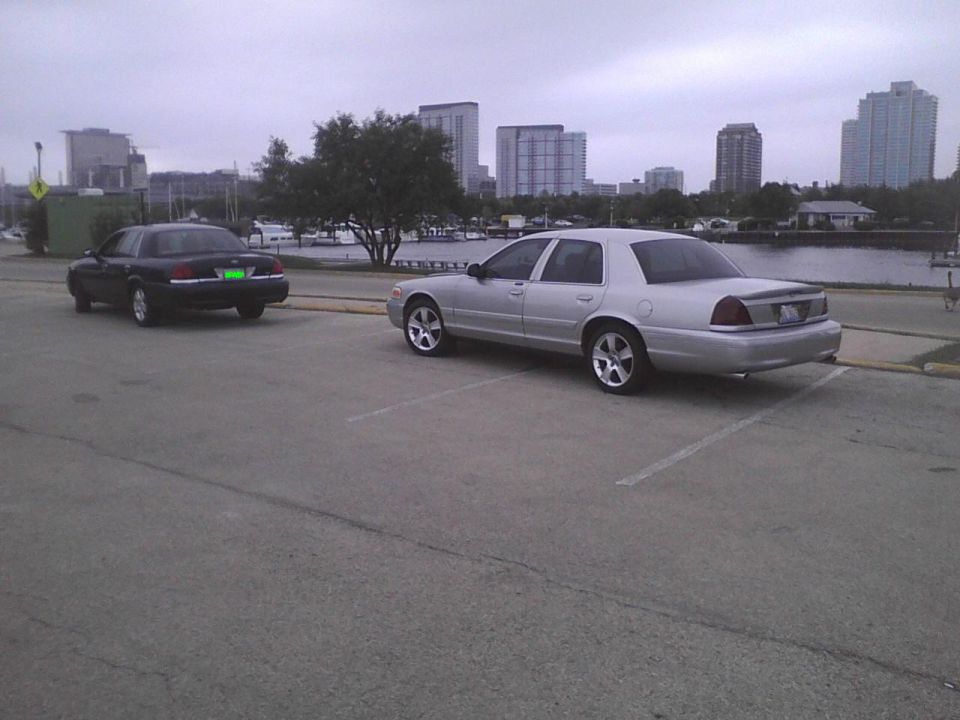 Silver 2003 Ford Crown Victoria parked in a lot, 3q-front view, with a black car behind it