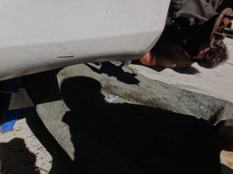 1993 Ford Taurus - Mechanic working on the wheel hub of a car supported by a jack stand.