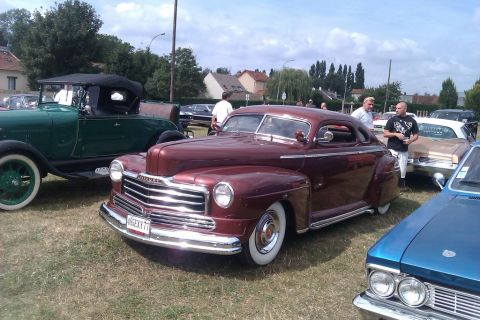 1991 Ford LTD Crown Victoria - A maroon 1946 coupe with a prominent chrome grille and whitewall tires is displayed at an outdoor event.