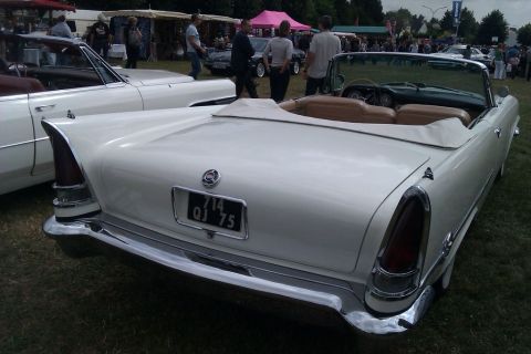 1991 Ford LTD Crown Victoria - A white convertible is parked on grass at an outdoor event with other vehicles and people in the background.