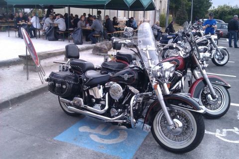 1991 Ford LTD Crown Victoria - Motorcycles are parked in a lot, with people dining at tables under a canopy in the background.