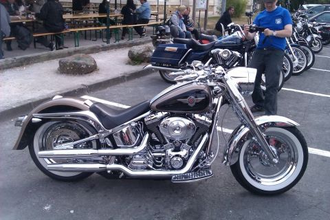 1991 Ford LTD Crown Victoria - A detailed view of a shiny Harley-Davidson motorcycle with whitewall tires, parked outdoors.