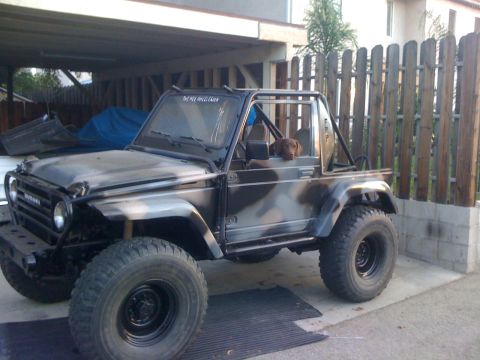 1987 Suzuki Samurai - This 1987 Suzuki Samurai has a custom camouflage paint job and a dog riding shotgun.