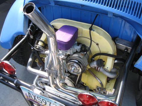 1970 Volkswagen Beetle - The engine bay of a blue Volkswagen Beetle shows a custom exhaust system and aftermarket air filter, suggesting a modified vehicle.