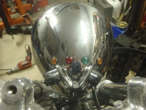 2002 Harley-Davidson XL Sportster - A close-up view of a shiny chrome motorcycle headlight assembly, three colored indicator lights.