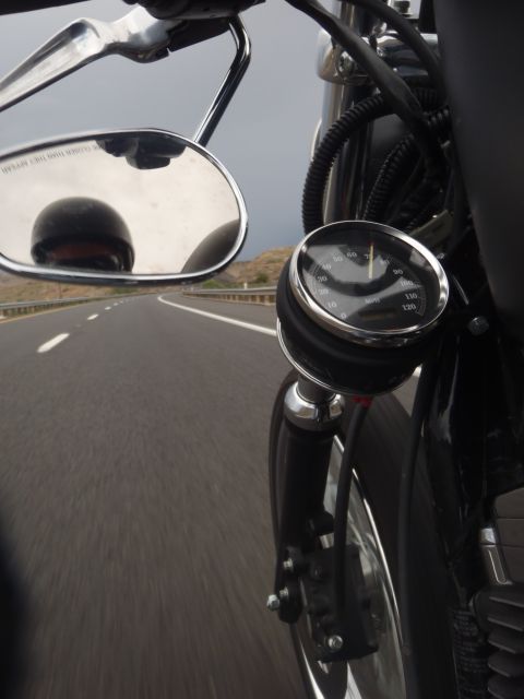 2002 Harley-Davidson XL Sportster - Speedometer on a motorcycle shows MPH while riding on a highway, with a rider's helmet reflected in the side mirror.
