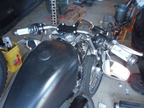 2002 Harley-Davidson XL Sportster - Close-up view of a black motorcycle's fuel tank and handlebars, white grips and chrome accents.