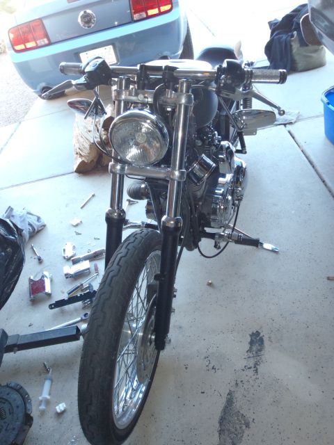 2002 Harley-Davidson XL Sportster - Front view of a motorcycle's front end, with various parts laid out on the concrete floor.
