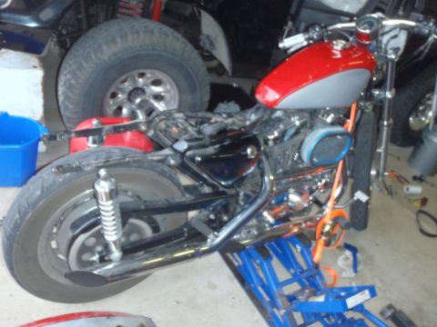 2002 Harley-Davidson XL Sportster - A motorcycle is shown on a lift in a garage setting, with other vehicles partially visible in the background.