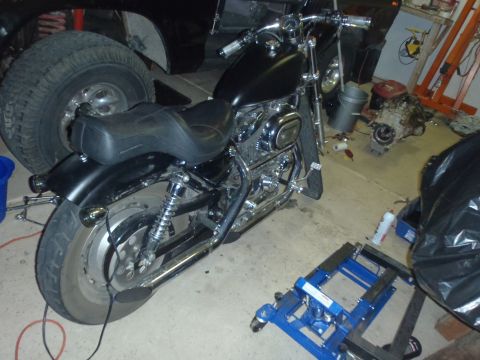 2002 Harley-Davidson XL Sportster - A black motorcycle is parked in a garage with tools and parts scattered around.