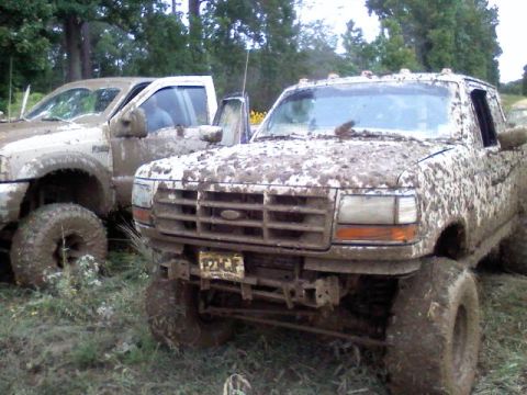 1993 Ford F-150 - Two muddy pickup trucks, including a 1993 Ford F-150, are seen off-roading in the mud.