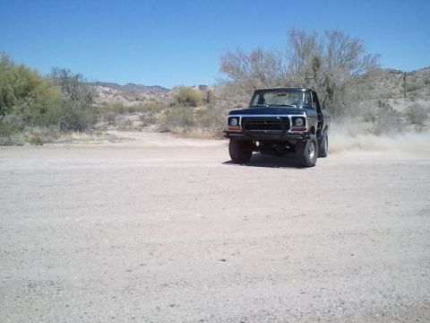 1978 Ford Bronco - A classic 1978 Ford Bronco navigates a dusty off-road path under a clear blue sky.