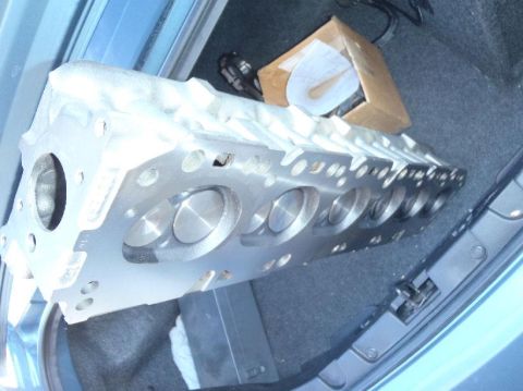 1978 Ford Bronco - An aluminum engine cylinder head is placed in the trunk of a car, alongside a cardboard box.