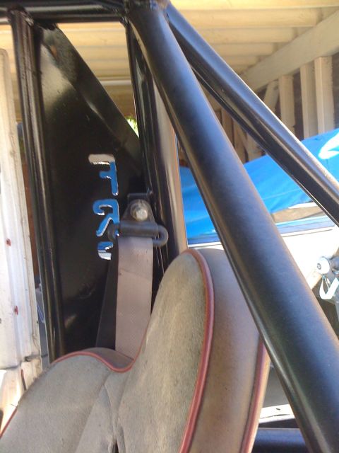 1987 Suzuki Samurai - Close-up view of a vehicle's interior, showing a roll cage and seatbelt assembly.