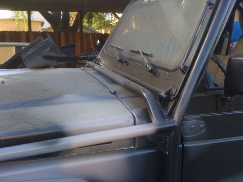 1987 Suzuki Samurai - Close-up of a dusty Suzuki Samurai's front end, showing the windshield and roll cage.