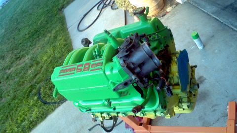 1987 Ford Bronco - A green Ford 5.8L engine is shown on an orange engine stand, with a carburetor and intake manifold attached.
