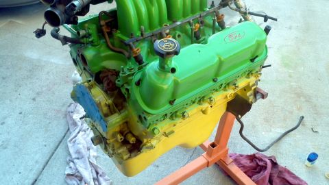 1987 Ford Bronco - A Ford V8 engine, painted green and yellow, is mounted on an engine stand.