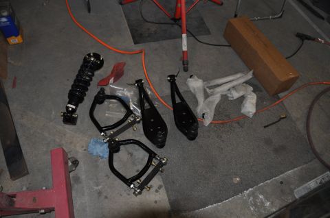 1971 Ford Mustang - Various automotive suspension components are arranged on the floor, ready for installation or repair.