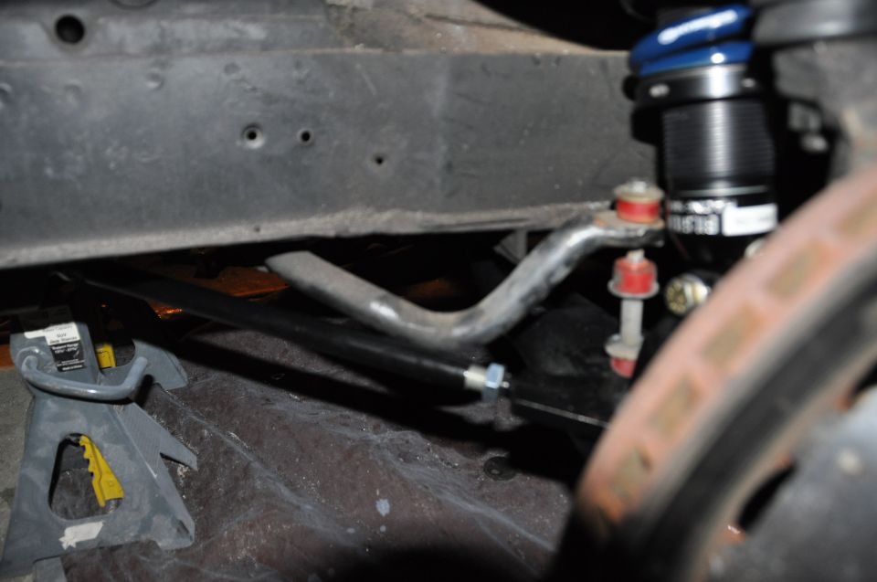 Car jack supporting frame near sway bar and shock absorber with blue spring