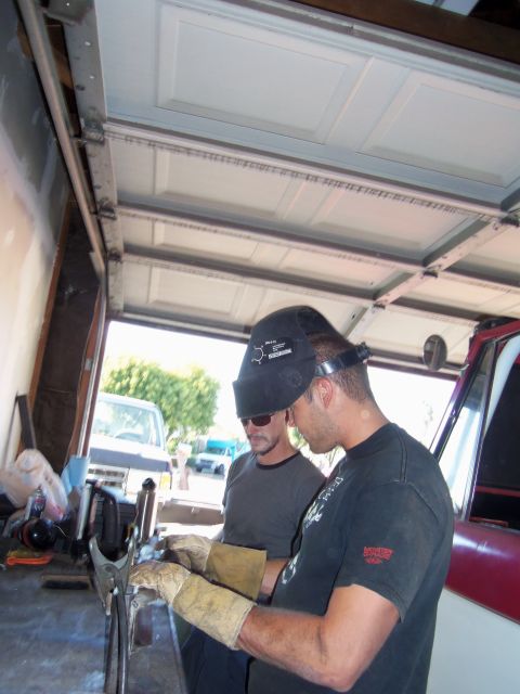 1968 Ford Bronco - Two men are working on a project in a garage, with a red vehicle and a white van visible.